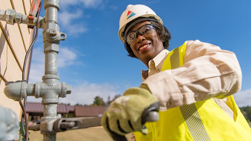 Black woman gas technician with wrenches working on pipe